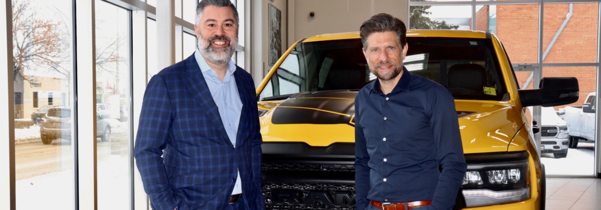 a photo op picture of two men standing in front of a yellow truck